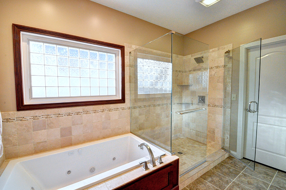 Cette photo montre une salle de bain principale chic en bois foncé avec un placard à porte shaker, une baignoire posée, une douche double, WC séparés, un carrelage beige, un mur beige, un lavabo encastré, un plan de toilette en granite, un sol multicolore et une cabine de douche à porte battante.