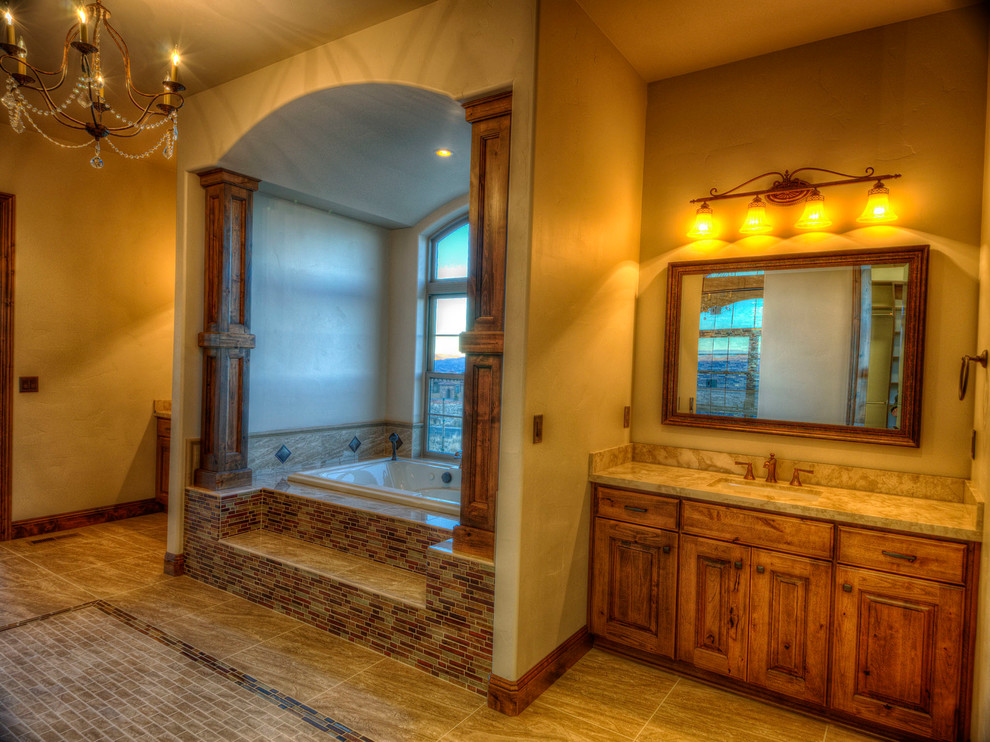 Пример оригинального дизайна: большая главная ванная комната в стиле рустика с фасадами с выступающей филенкой, фасадами цвета дерева среднего тона, бежевой плиткой, коричневой плиткой, разноцветной плиткой, удлиненной плиткой, коричневыми стенами, полом из керамогранита, врезной раковиной, столешницей из гранита и гидромассажной ванной
