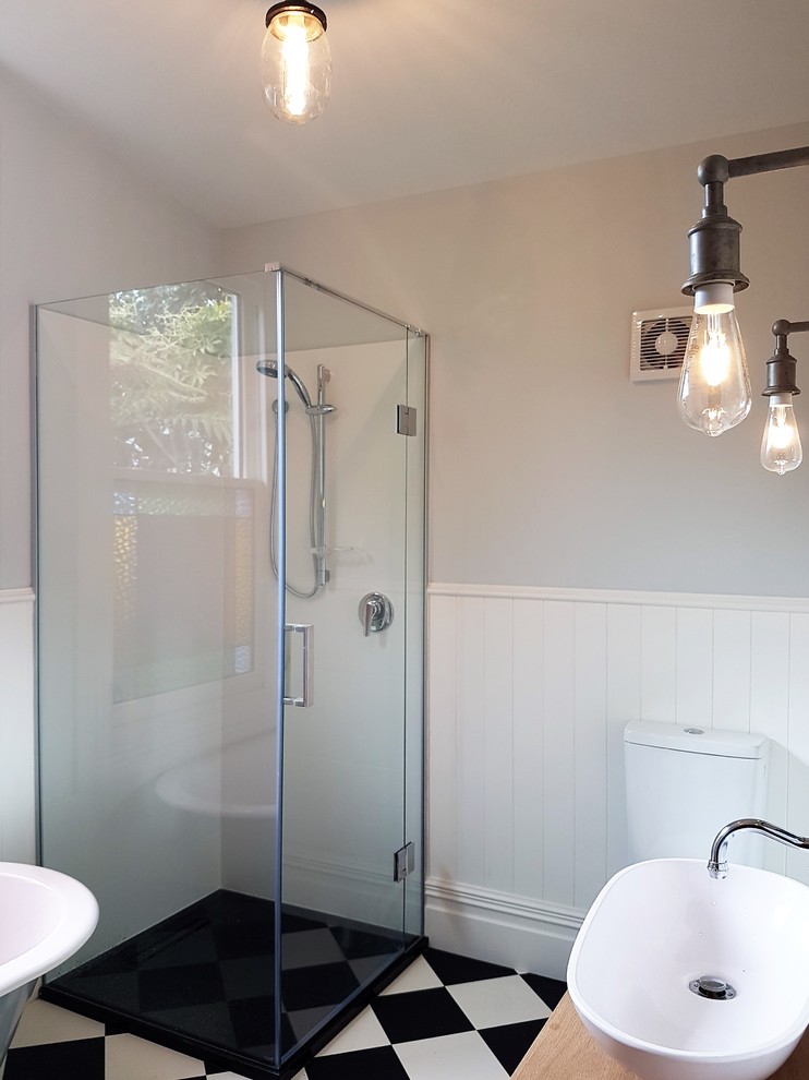 Photo of a medium sized victorian ensuite bathroom in Christchurch with freestanding cabinets, medium wood cabinets, a corner bath, a corner shower, black and white tiles, multi-coloured walls, a vessel sink and wooden worktops.