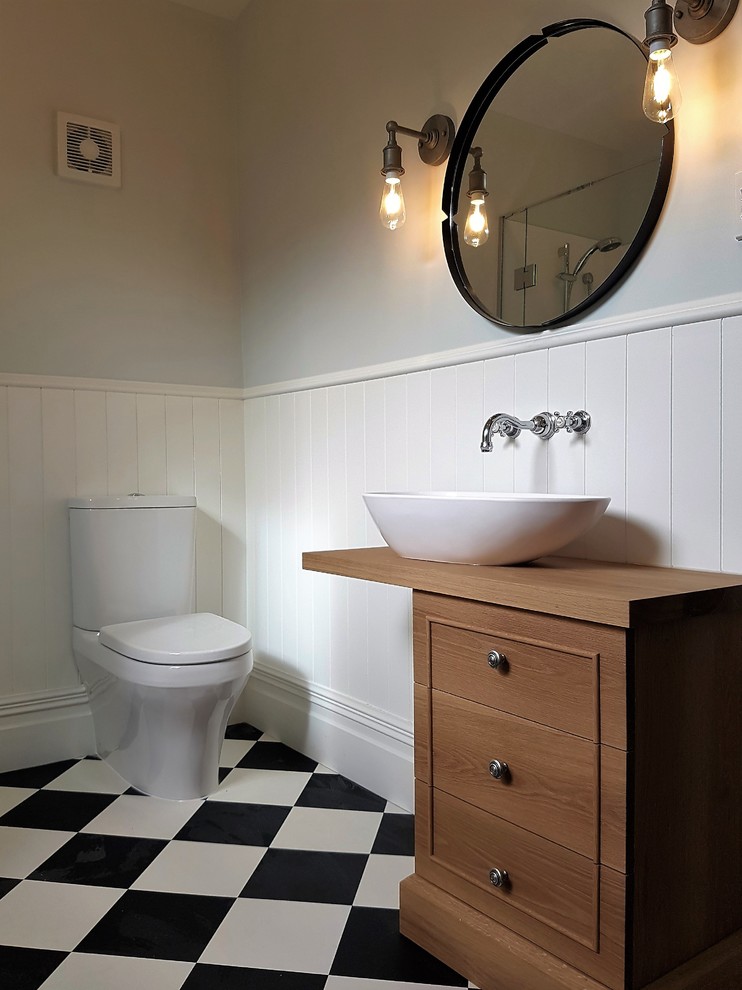 Cette photo montre une salle de bain principale victorienne en bois brun de taille moyenne avec un placard en trompe-l'oeil, une baignoire d'angle, une douche d'angle, un carrelage noir et blanc, un mur multicolore, une vasque et un plan de toilette en bois.