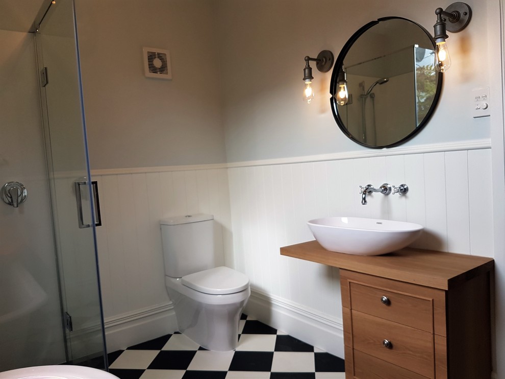 Inspiration for a medium sized victorian ensuite bathroom in Christchurch with freestanding cabinets, medium wood cabinets, a claw-foot bath, a corner shower, a two-piece toilet, multi-coloured walls, vinyl flooring, a vessel sink, wooden worktops, multi-coloured floors and a hinged door.