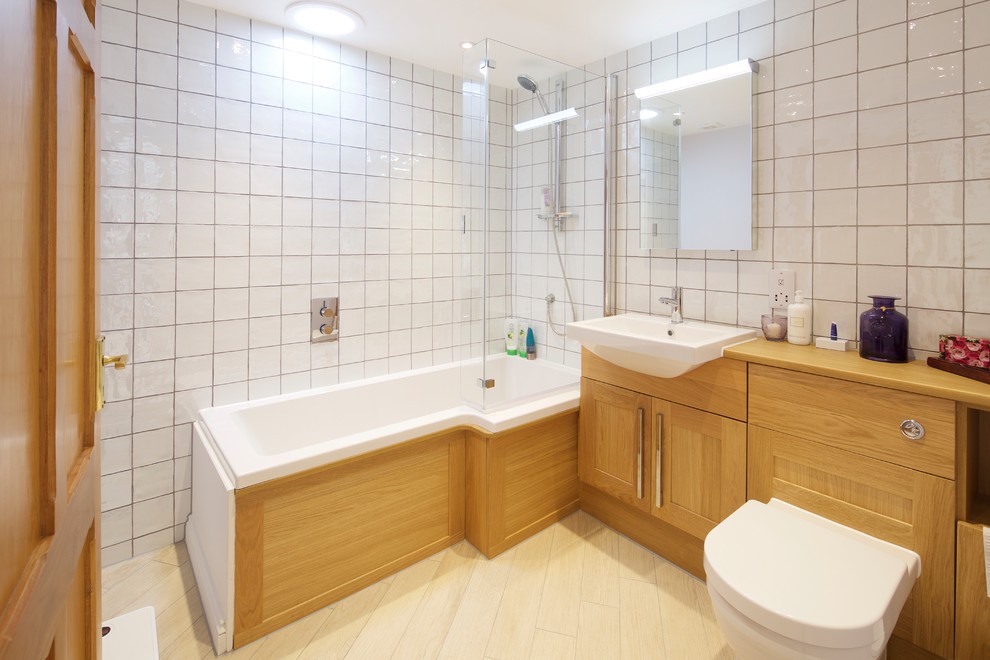 Foto på ett medelhavsstil beige en-suite badrum, med skåp i shakerstil, skåp i ljust trä, ett hörnbadkar, en dusch/badkar-kombination, en toalettstol med hel cisternkåpa, vit kakel, ett fristående handfat, träbänkskiva och beiget golv