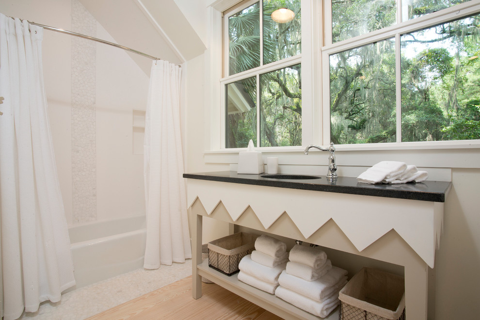 Foto på ett mellanstort maritimt badrum, med ett undermonterad handfat, öppna hyllor, vita skåp, granitbänkskiva, ett platsbyggt badkar, en dusch/badkar-kombination, vit kakel, keramikplattor, vita väggar, ljust trägolv och dusch med duschdraperi