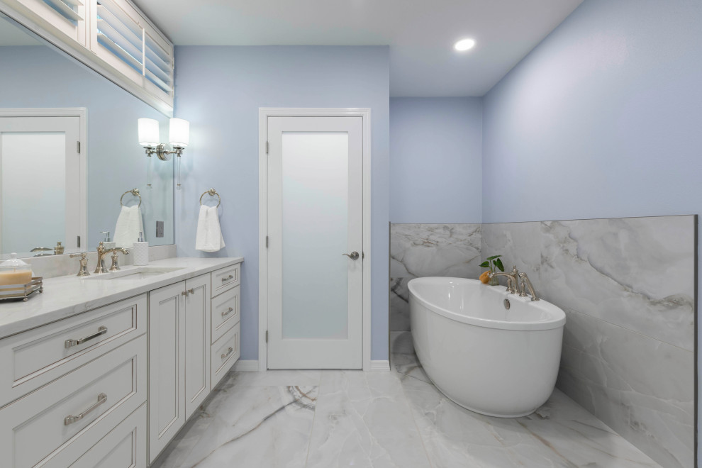 Пример оригинального дизайна: большая главная ванная комната в стиле неоклассика (современная классика) с фасадами с утопленной филенкой, бежевыми фасадами, отдельно стоящей ванной, открытым душем, раздельным унитазом, разноцветной плиткой, керамогранитной плиткой, синими стенами, мраморным полом, врезной раковиной, столешницей из кварцита, разноцветным полом, открытым душем, белой столешницей, сиденьем для душа, тумбой под две раковины и встроенной тумбой