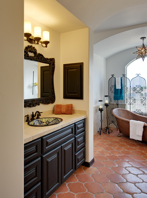 Пример оригинального дизайна: главная ванная комната в средиземноморском стиле с накладной раковиной, темными деревянными фасадами, столешницей из плитки, ванной на ножках, бежевой плиткой и керамогранитной плиткой