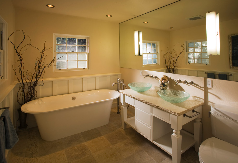 Пример оригинального дизайна: главная ванная комната в классическом стиле с плоскими фасадами, белыми фасадами, отдельно стоящей ванной, раздельным унитазом, керамической плиткой, бежевыми стенами, полом из известняка, настольной раковиной и столешницей из известняка