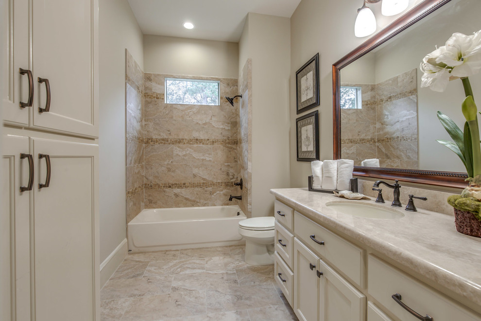 Mid-sized tuscan master beige tile and ceramic tile ceramic tile and beige floor bathroom photo in Houston with recessed-panel cabinets, white cabinets, a one-piece toilet, beige walls and an undermount sink