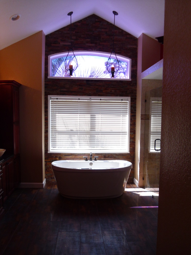 Cette image montre une grande salle de bain principale chalet en bois foncé avec une vasque, un placard en trompe-l'oeil, un plan de toilette en stéatite, une baignoire indépendante, une douche d'angle, un carrelage beige, des carreaux de céramique, un mur orange et un sol en travertin.