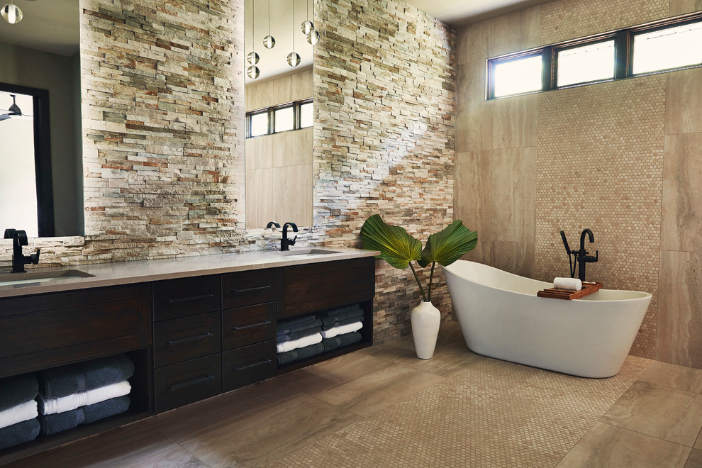 Cette photo montre une grande salle de bain principale tendance en bois foncé avec un placard à porte shaker, une baignoire indépendante, un carrelage beige, des carreaux de porcelaine, un mur beige, un sol en carrelage de porcelaine, un lavabo encastré et un sol beige.