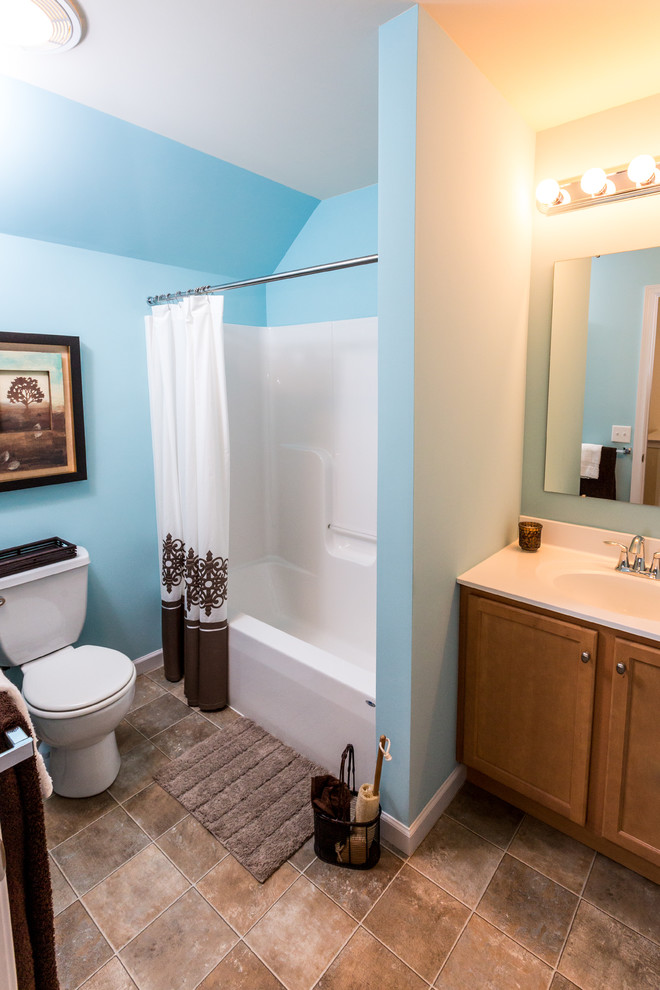 Esempio di una stanza da bagno tradizionale di medie dimensioni con lavabo integrato, ante in legno scuro, top in marmo, vasca/doccia, WC monopezzo, pareti blu e pavimento in linoleum