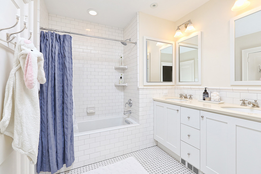 Klassisk inredning av ett stort badrum med dusch, med skåp i shakerstil, vita skåp, en dusch/badkar-kombination, en toalettstol med separat cisternkåpa, vit kakel, tunnelbanekakel, beige väggar, ett undermonterad handfat, bänkskiva i akrylsten, flerfärgat golv och dusch med duschdraperi