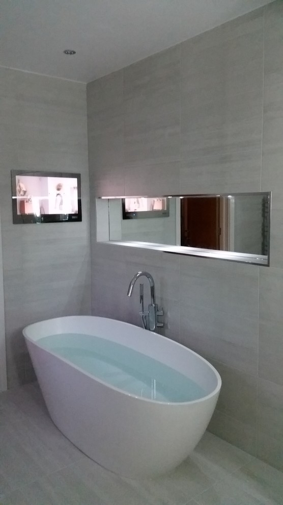 Bild på ett stort funkis badrum för barn, med släta luckor, vita skåp, ett fristående badkar, en öppen dusch, en bidé, grå kakel, mosaik och klinkergolv i porslin