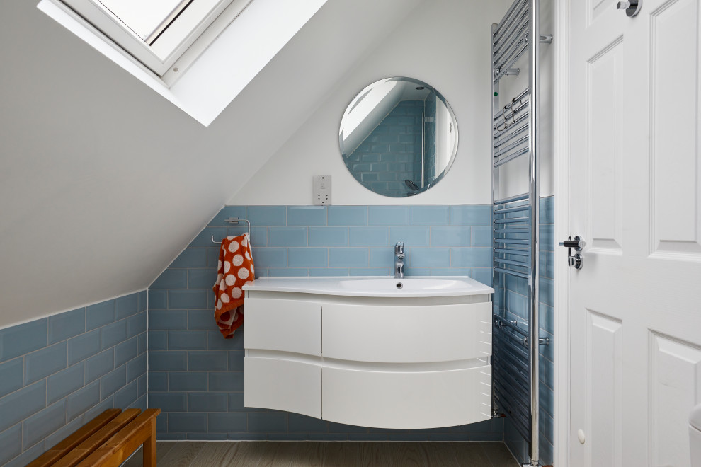 Exemple d'une salle de bain tendance de taille moyenne avec des portes de placard blanches, une douche d'angle, WC à poser, un carrelage bleu, des carreaux de céramique, un mur bleu, un sol en bois brun, un lavabo posé, un sol beige et meuble simple vasque.