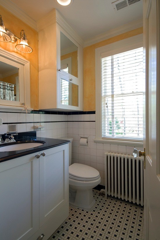Cette photo montre une petite salle de bain chic pour enfant avec un placard à porte shaker, des portes de placard blanches, un carrelage noir et blanc, des carreaux de céramique, un mur jaune, carreaux de ciment au sol, un lavabo encastré et un plan de toilette en granite.