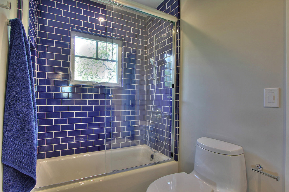 Ispirazione per una stanza da bagno per bambini classica di medie dimensioni con vasca ad alcova, vasca/doccia, WC monopezzo, piastrelle blu, piastrelle diamantate e pareti grigie