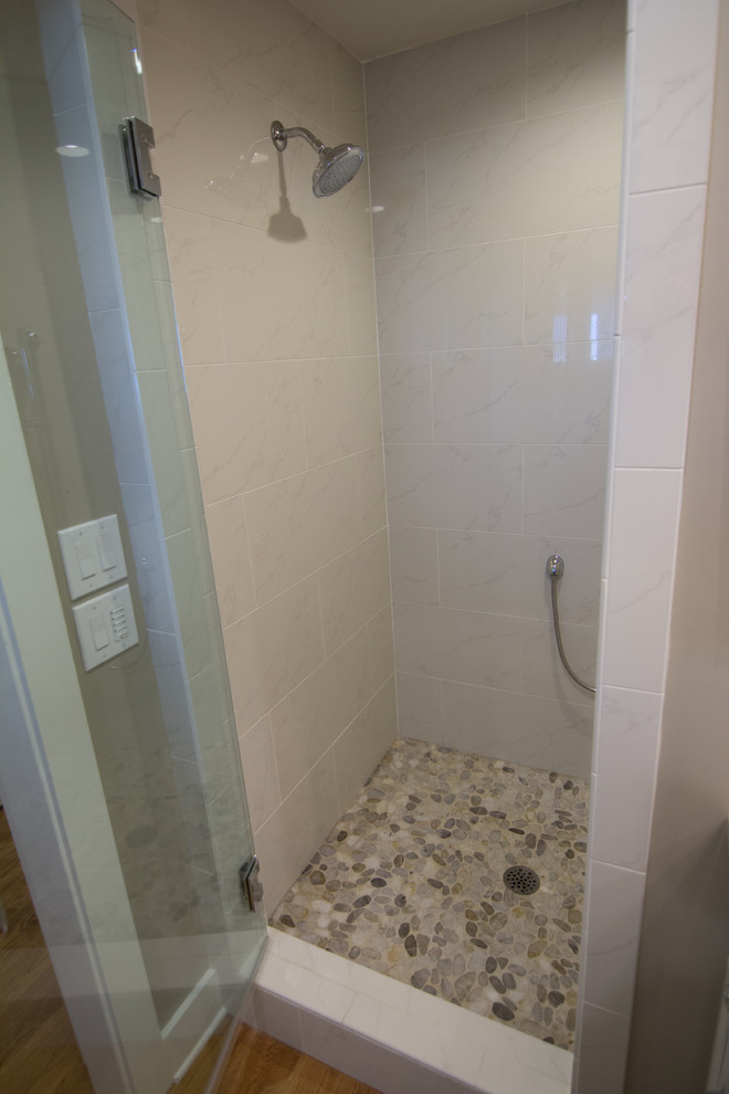 This is an example of a small coastal ensuite bathroom in Miami with recessed-panel cabinets, beige cabinets, an alcove shower, grey tiles, grey walls, medium hardwood flooring, a submerged sink and engineered stone worktops.
