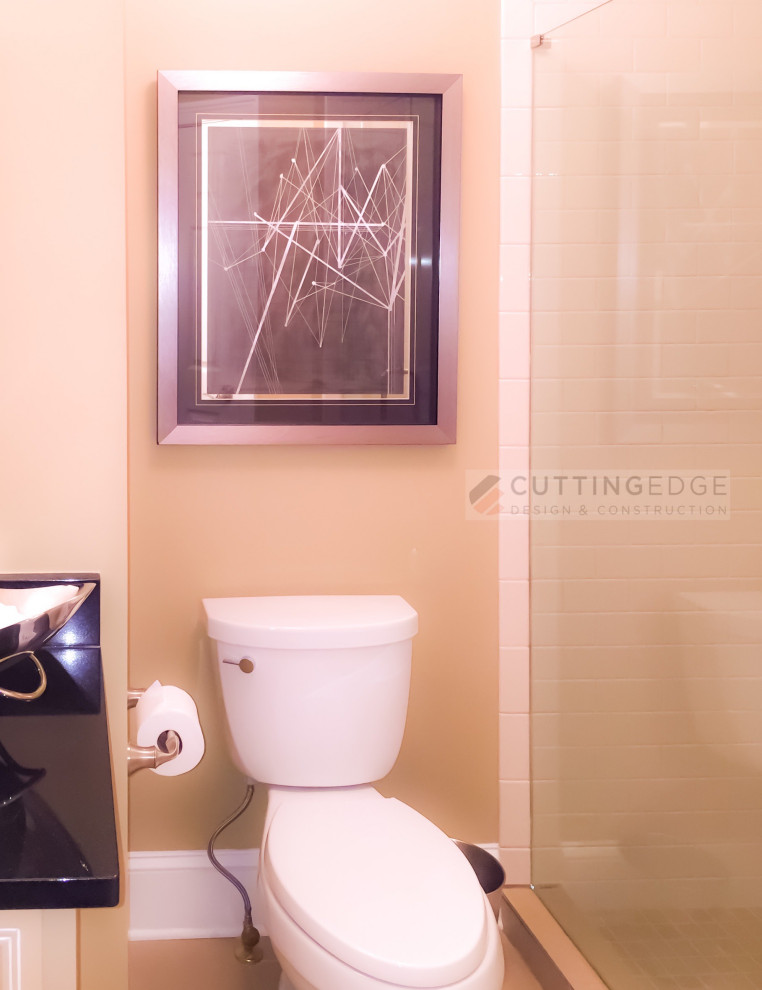 Aménagement d'une salle de bain classique de taille moyenne avec un placard avec porte à panneau surélevé, des portes de placard beiges, WC séparés, un carrelage beige, des carreaux de céramique, un mur beige, un sol en carrelage de porcelaine, un lavabo encastré, un plan de toilette en granite, un sol beige, une cabine de douche à porte battante, un plan de toilette noir, meuble simple vasque et meuble-lavabo encastré.