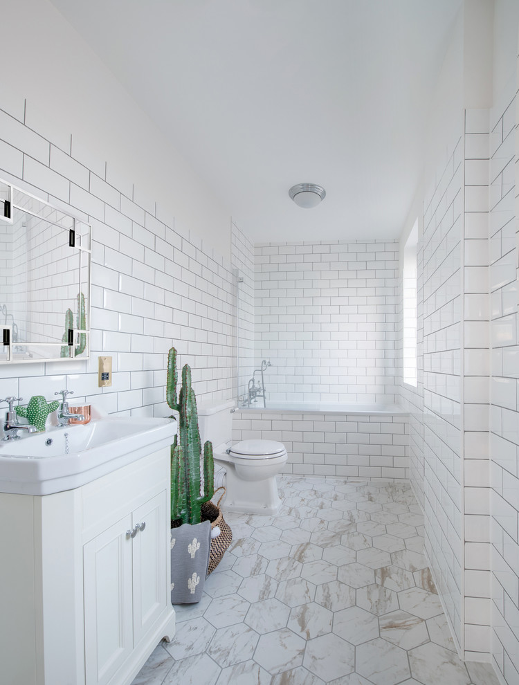 ロンドンにある広いコンテンポラリースタイルのおしゃれなバスルーム (浴槽なし) (落し込みパネル扉のキャビネット、白いキャビネット、アルコーブ型浴槽、シャワー付き浴槽	、一体型トイレ	、白いタイル、サブウェイタイル、白い壁、コンソール型シンク、ベージュの床) の写真