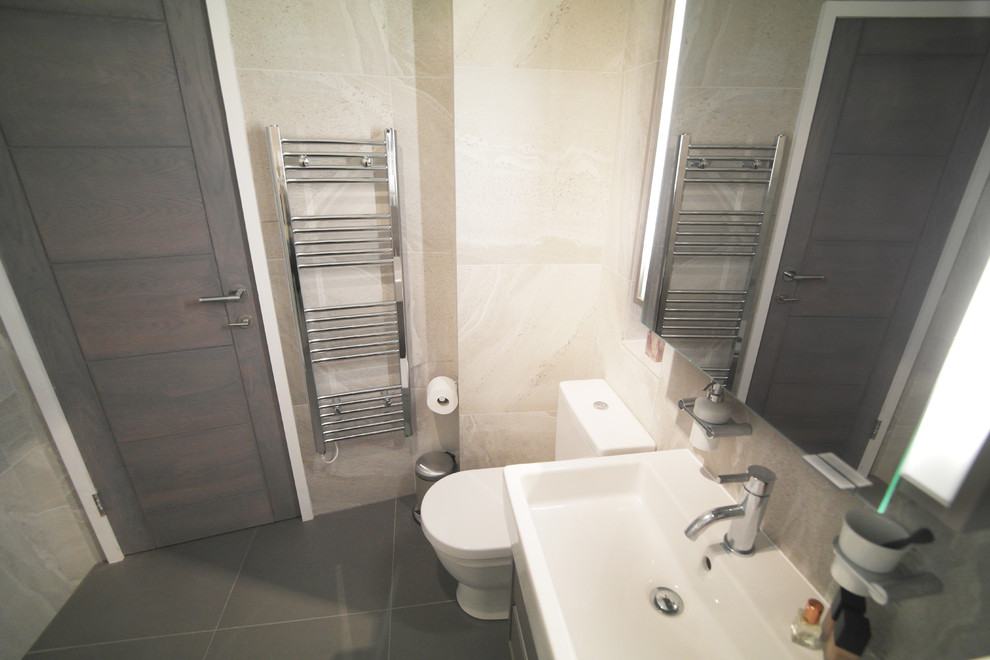 Medium sized contemporary shower room bathroom in London with glass-front cabinets, grey cabinets, a corner shower, a one-piece toilet, grey tiles, porcelain tiles, a wall-mounted sink and tiled worktops.