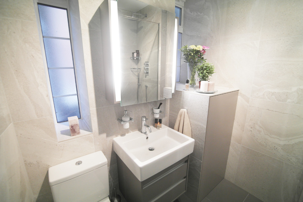 Foto di una stanza da bagno con doccia minimal di medie dimensioni con ante di vetro, ante grigie, doccia ad angolo, WC monopezzo, piastrelle grigie, piastrelle in gres porcellanato, lavabo sospeso e top piastrellato