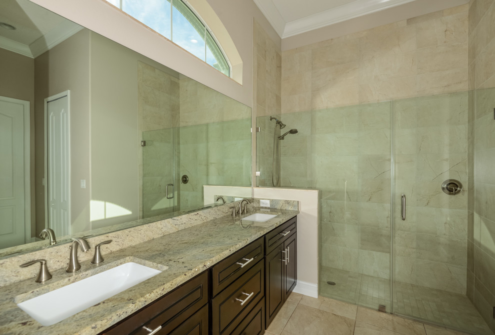 This is an example of a large classic ensuite bathroom in Tampa with raised-panel cabinets, a built-in shower, a one-piece toilet, beige tiles, travertine tiles, white walls, travertine flooring, a submerged sink, granite worktops, beige floors, a hinged door and beige worktops.