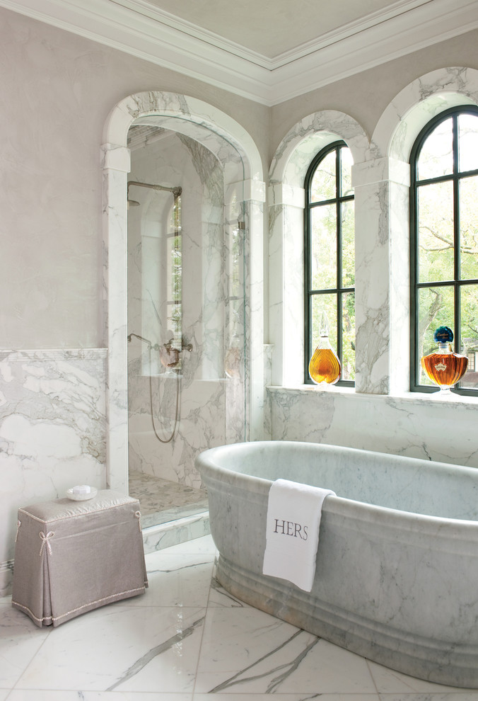 Foto di una stanza da bagno mediterranea con vasca freestanding, doccia alcova, piastrelle bianche, piastrelle di marmo, pareti grigie, pavimento bianco e porta doccia a battente