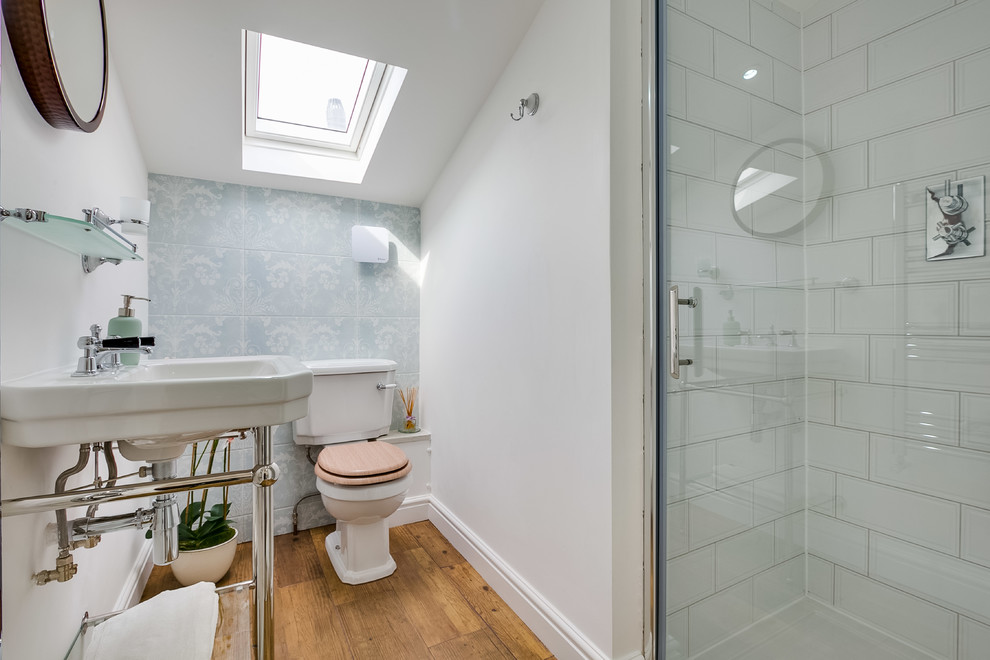 ロンドンにある小さなトランジショナルスタイルのおしゃれなバスルーム (浴槽なし) (アルコーブ型シャワー、分離型トイレ、青いタイル、白いタイル、セラミックタイル、白い壁、無垢フローリング、コンソール型シンク、開き戸のシャワー) の写真