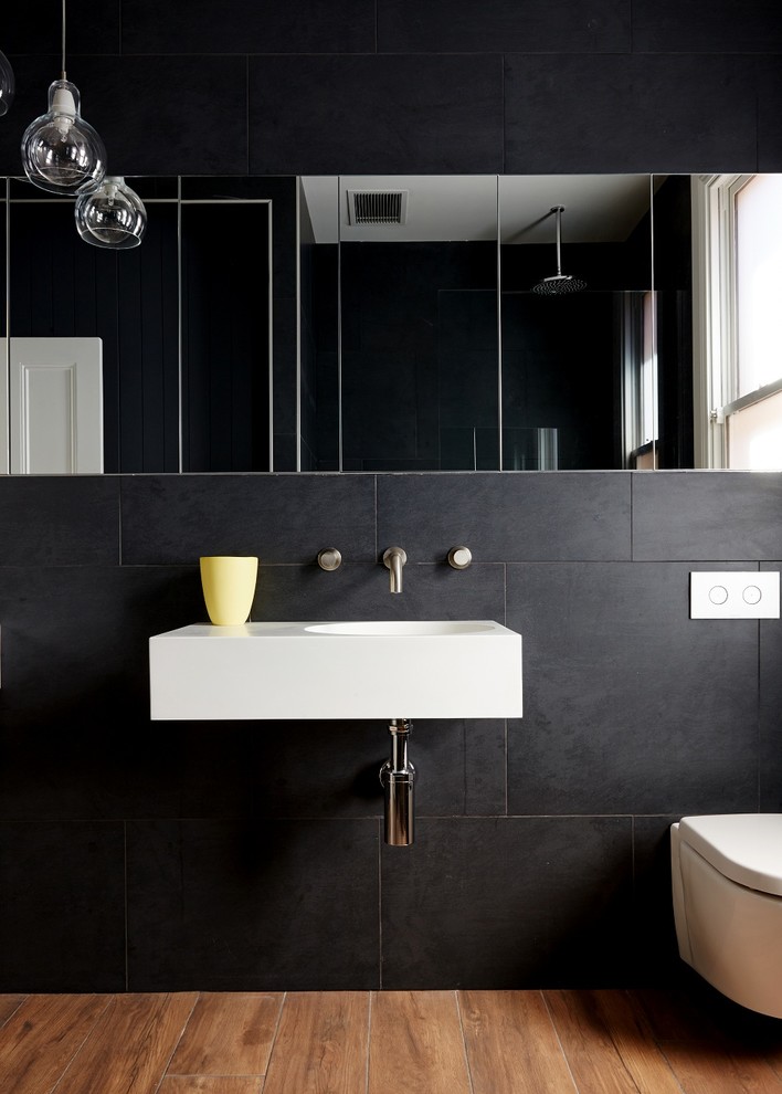 Cette photo montre une salle de bain principale tendance de taille moyenne avec WC suspendus, un carrelage noir, un mur noir et un lavabo suspendu.