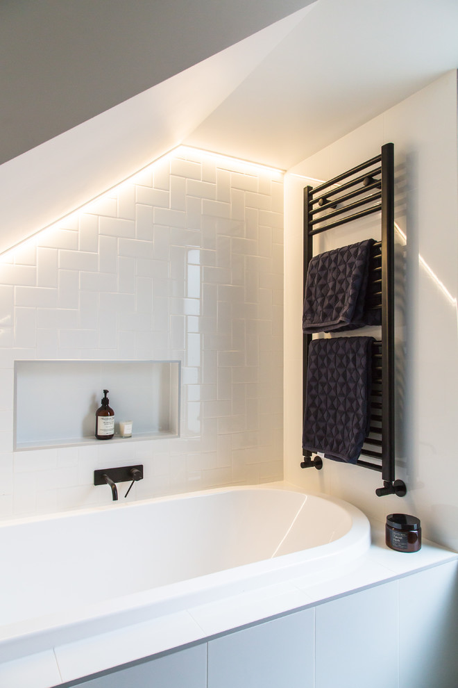 Cette image montre une petite salle de bain design pour enfant avec une baignoire posée, un carrelage blanc, des carreaux de céramique, un mur blanc et un sol gris.