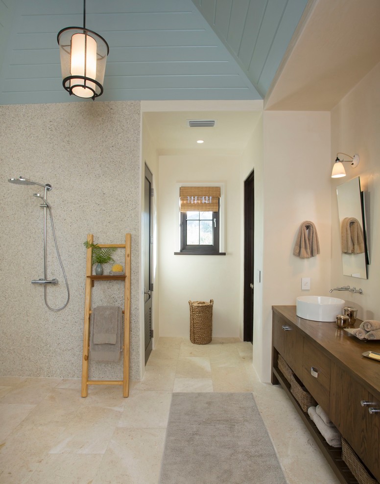 Cette photo montre une salle de bain principale exotique en bois foncé avec une vasque, un placard à porte plane, une douche ouverte, un plan de toilette en bois, un carrelage beige, un mur beige et aucune cabine.