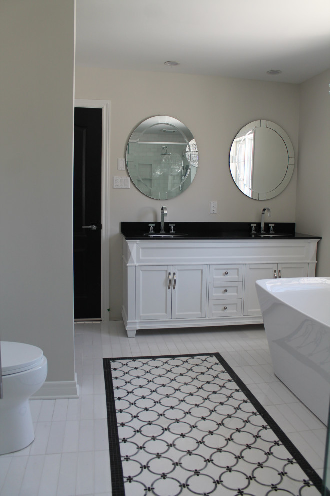 Bild på ett stort vintage svart svart en-suite badrum, med vita skåp, ett fristående badkar, en hörndusch, en toalettstol med hel cisternkåpa, vit kakel, porslinskakel, grå väggar, marmorgolv, ett undermonterad handfat, bänkskiva i kvartsit, vitt golv och dusch med gångjärnsdörr