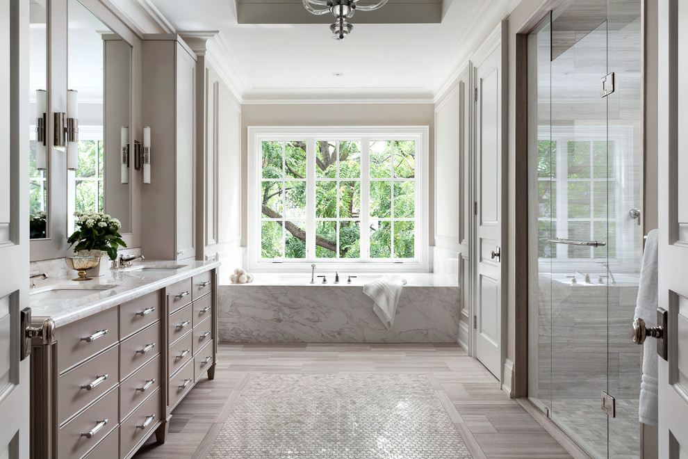 Стильный дизайн: ванная комната в стиле неоклассика (современная классика) с врезной раковиной, серыми фасадами, ванной в нише, душем в нише, бежевыми стенами, окном и плоскими фасадами - последний тренд
