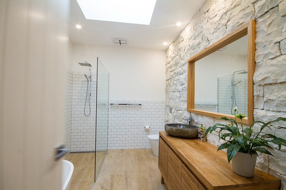 Стильный дизайн: ванная комната в современном стиле с фасадами островного типа, фасадами цвета дерева среднего тона, отдельно стоящей ванной, открытым душем, белой плиткой, полом из керамической плитки, консольной раковиной и открытым душем - последний тренд