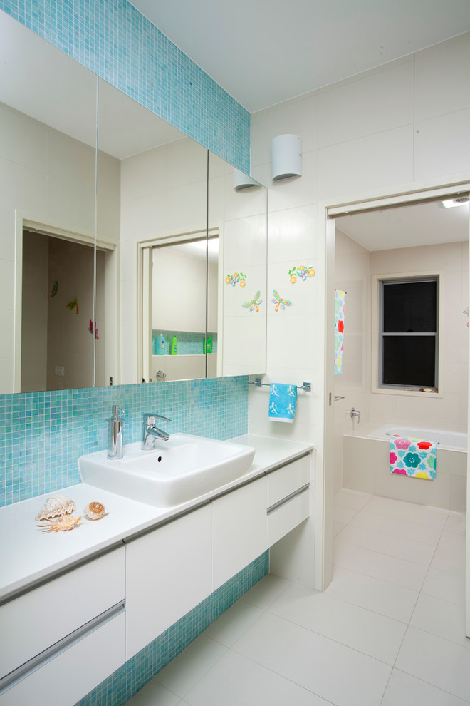 Idéer för att renovera ett stort funkis badrum för barn, med vita skåp, blå kakel, mosaik, ett platsbyggt badkar, en vägghängd toalettstol, vita väggar, klinkergolv i porslin, bänkskiva i kvarts och ett fristående handfat