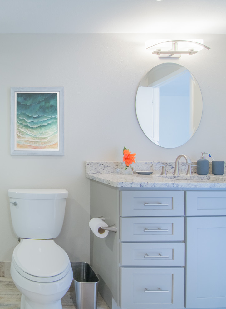 Small beach style bathroom in Tampa with shaker cabinets, grey cabinets, a walk-in shower, a wall mounted toilet, beige tiles, porcelain tiles, grey walls, porcelain flooring, a built-in sink and granite worktops.
