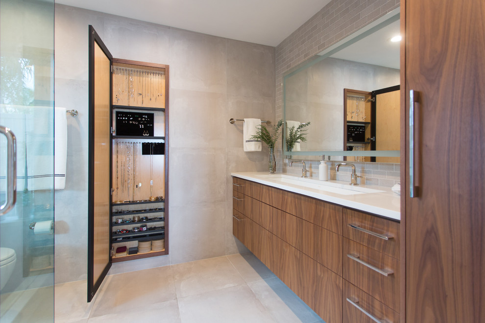 Modernes Badezimmer En Suite mit flächenbündigen Schrankfronten, hellbraunen Holzschränken, Toilette mit Aufsatzspülkasten, grauen Fliesen, weißer Wandfarbe, Keramikboden, Unterbauwaschbecken und Quarzwerkstein-Waschtisch in Tampa