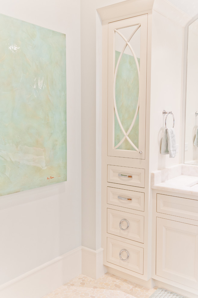 Cette image montre une salle de bain principale marine de taille moyenne avec un placard à porte affleurante, des portes de placard blanches, un carrelage blanc et un plan de toilette en marbre.