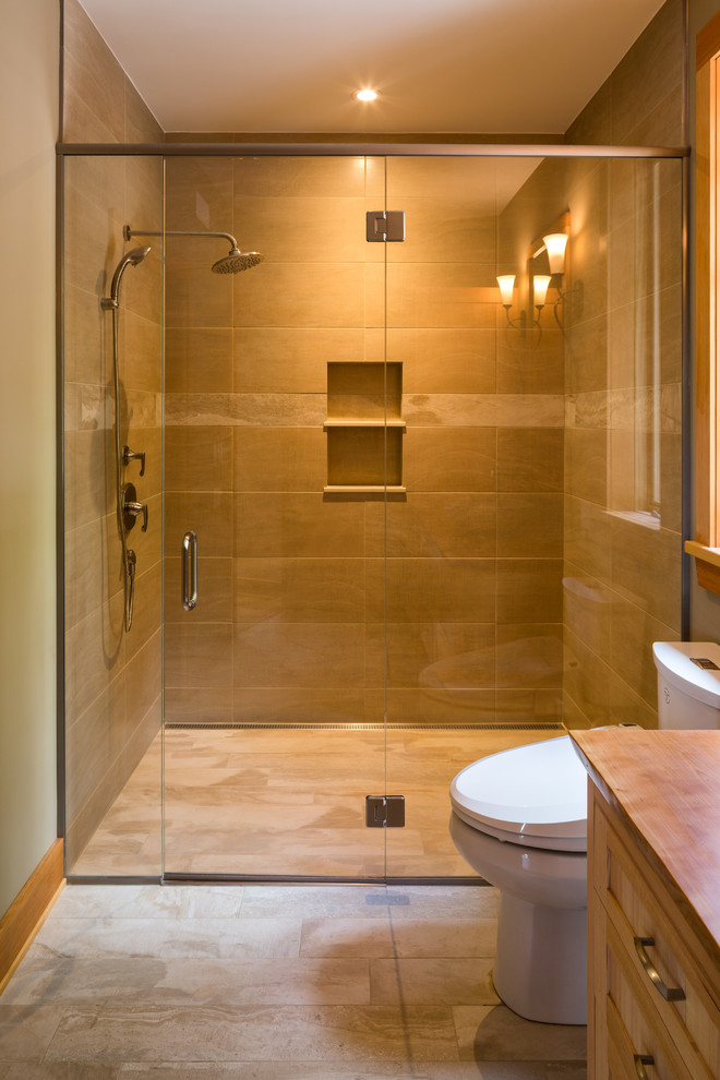 This is an example of a medium sized traditional ensuite bathroom in Ottawa with shaker cabinets, light wood cabinets, wooden worktops, beige tiles, porcelain tiles, a built-in shower, a bidet, a vessel sink, beige walls and ceramic flooring.