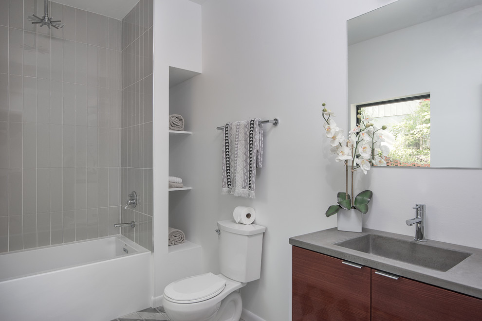 Idéer för mellanstora funkis badrum med dusch, med släta luckor, skåp i mörkt trä, ett badkar i en alkov, en dusch/badkar-kombination, en toalettstol med separat cisternkåpa, grå kakel, tunnelbanekakel, vita väggar, klinkergolv i keramik, ett integrerad handfat, bänkskiva i täljsten, grått golv och dusch med duschdraperi