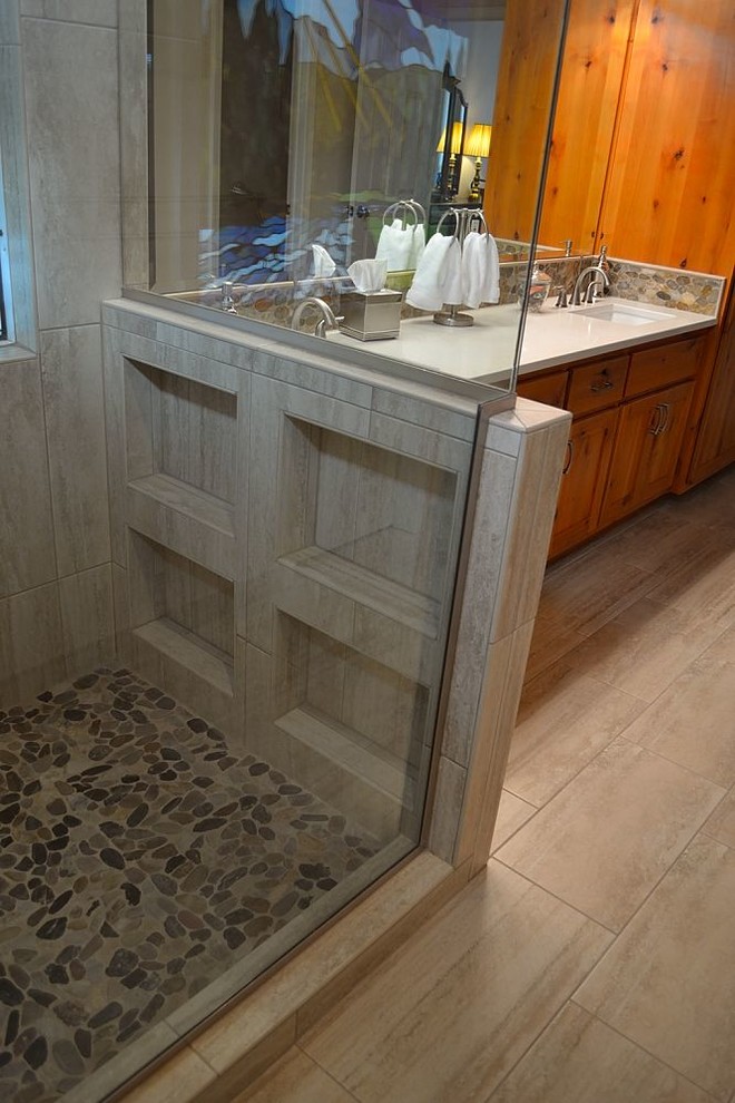 Example of a small mountain style master pebble tile laminate floor and beige floor corner shower design in Austin with shaker cabinets, medium tone wood cabinets, white walls, an undermount sink, laminate countertops and a hinged shower door