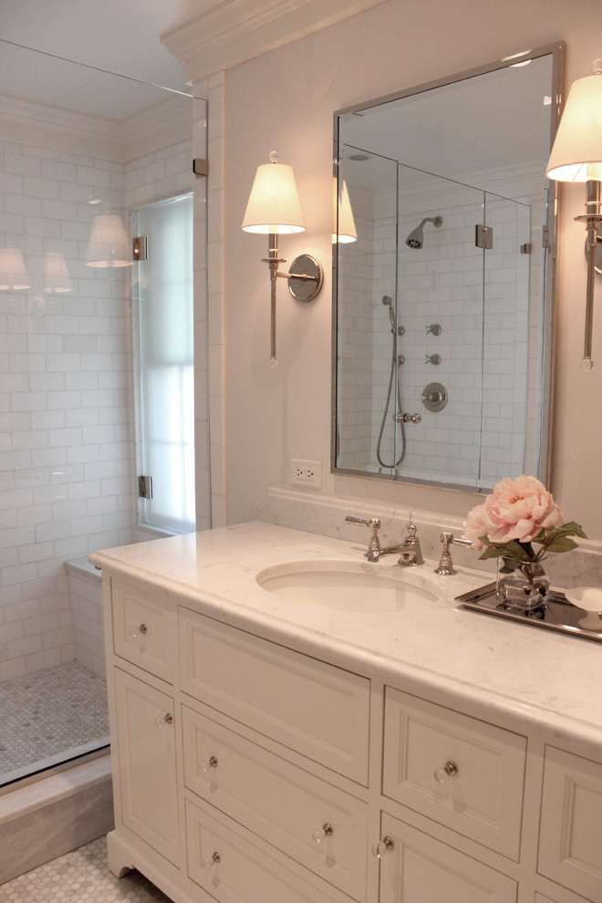 Пример оригинального дизайна: ванная комната в классическом стиле с фасадами с утопленной филенкой, белыми фасадами, душем в нише, раздельным унитазом, белой плиткой, мраморной плиткой, серыми стенами, мраморным полом, душевой кабиной, врезной раковиной, мраморной столешницей, серым полом и душем с распашными дверями