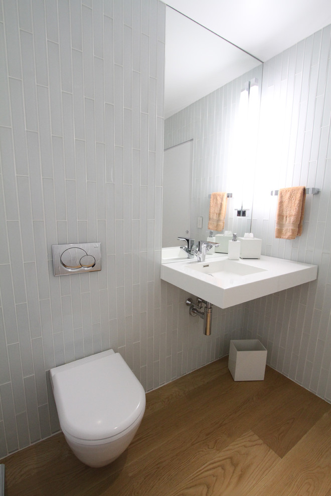 Foto di un bagno di servizio minimal con lavabo integrato, WC monopezzo, piastrelle grigie, piastrelle diamantate e pareti grigie
