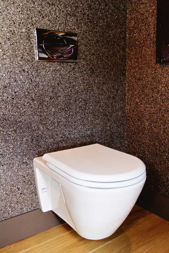 Immagine di un bagno di servizio minimal con lavabo a bacinella, ante in legno chiaro, top in legno, WC monopezzo e pareti multicolore
