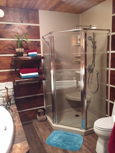 Imagen de cuarto de baño principal rústico de tamaño medio con bañera encastrada, ducha esquinera, sanitario de una pieza, paredes marrones y suelo de madera en tonos medios