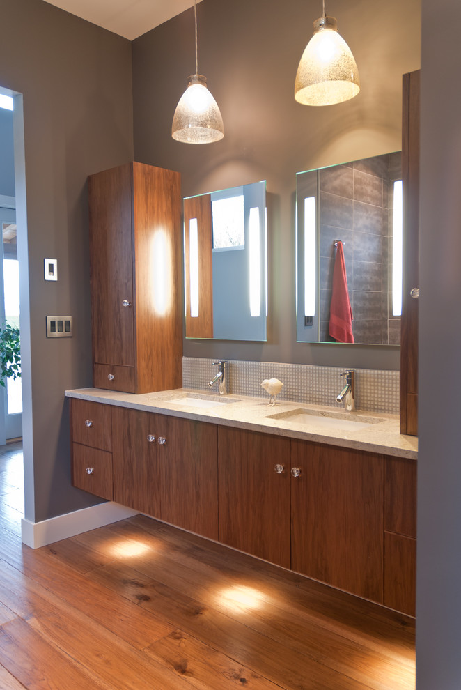 Cette image montre une salle de bain design en bois foncé avec un lavabo encastré, un placard à porte plane, un plan de toilette en quartz modifié et un carrelage en pâte de verre.