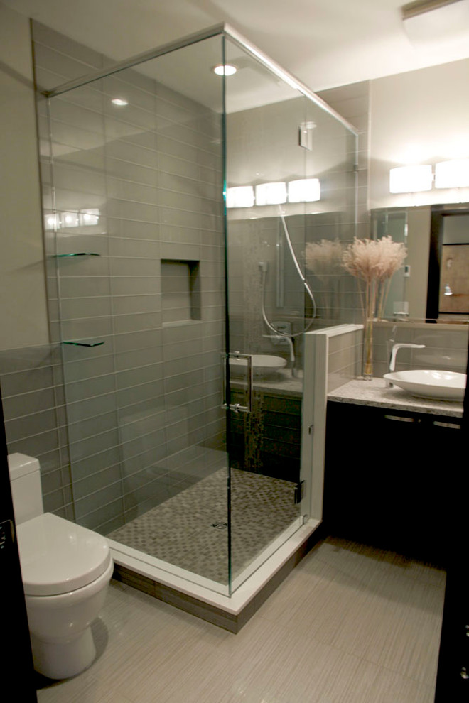 Cette photo montre une petite salle de bain moderne en bois foncé avec une vasque, un placard à porte plane, un plan de toilette en quartz modifié, une douche d'angle, WC à poser, un carrelage noir et des carreaux de porcelaine.