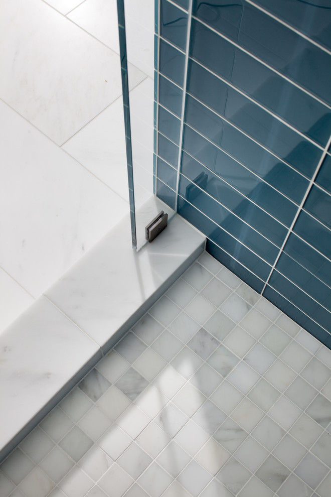 Cette photo montre une salle de bain principale moderne de taille moyenne avec un placard à porte affleurante, des portes de placard grises, une baignoire posée, une douche d'angle, WC à poser, un carrelage beige, un carrelage en pâte de verre, un mur bleu, un sol en marbre, un lavabo intégré, un plan de toilette en quartz modifié, un sol blanc et une cabine de douche à porte battante.