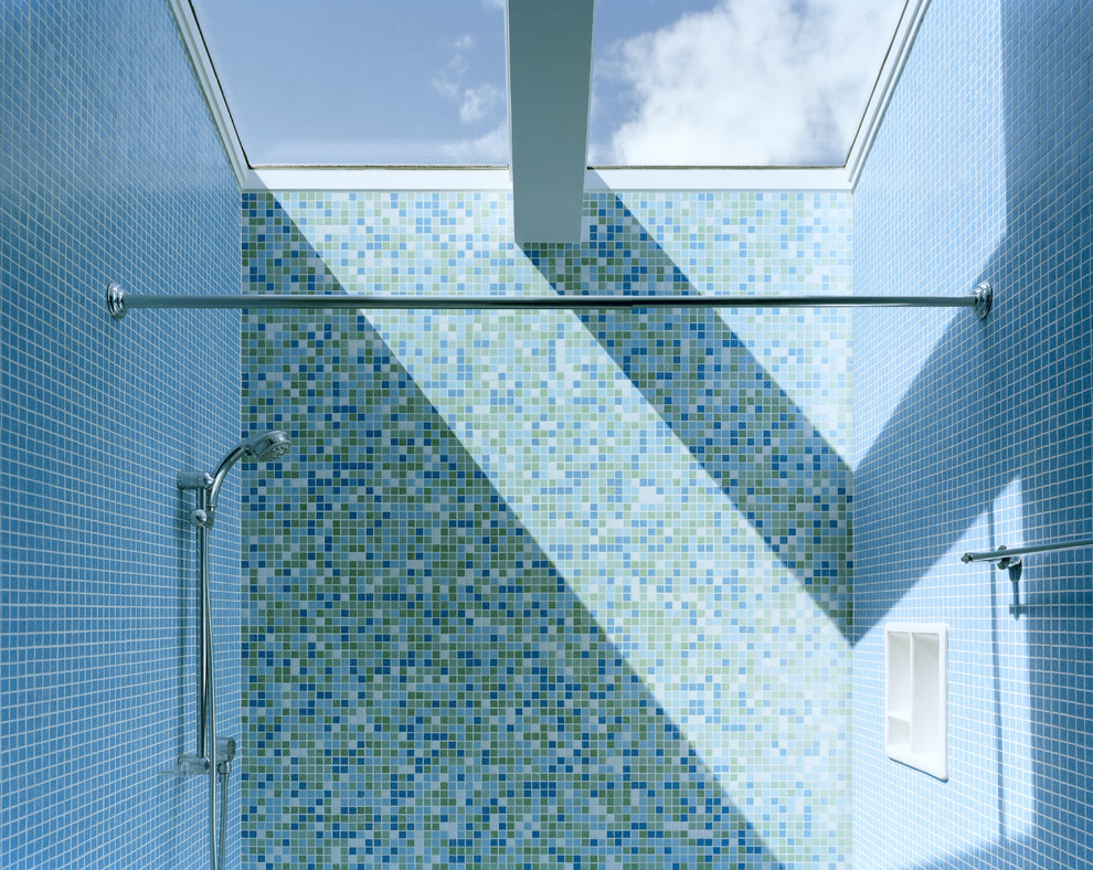 Kleines Modernes Badezimmer mit flächenbündigen Schrankfronten, weißen Schränken, Badewanne in Nische, Duschbadewanne, Wandtoilette mit Spülkasten, blauen Fliesen, Mosaikfliesen, blauer Wandfarbe, Mosaik-Bodenfliesen, integriertem Waschbecken und Mineralwerkstoff-Waschtisch in San Francisco