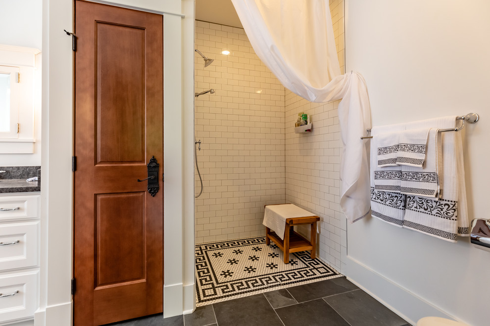 Пример оригинального дизайна: главная ванная комната в викторианском стиле с фасадами с утопленной филенкой, белыми фасадами, ванной на ножках, открытым душем, унитазом-моноблоком, белой плиткой, керамической плиткой, белыми стенами, полом из сланца, врезной раковиной, столешницей из гранита, серым полом, шторкой для ванной и черной столешницей