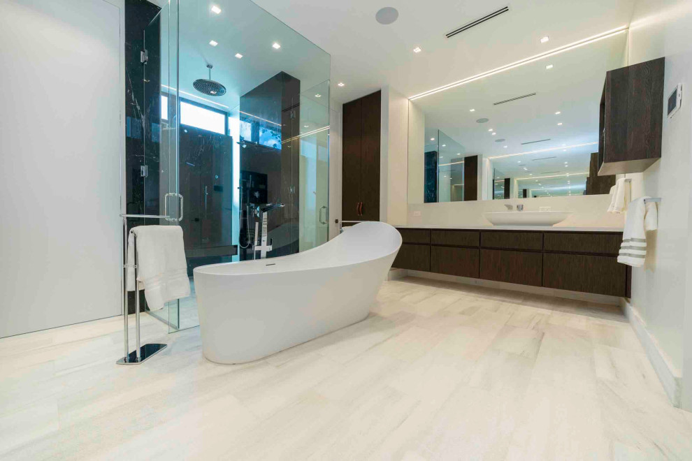 Inspiration för stora moderna vitt en-suite badrum, med möbel-liknande, skåp i mörkt trä, ett fristående badkar, en dubbeldusch, en vägghängd toalettstol, svart kakel, stenhäll, vita väggar, marmorgolv, ett fristående handfat, bänkskiva i kvarts, vitt golv och dusch med gångjärnsdörr